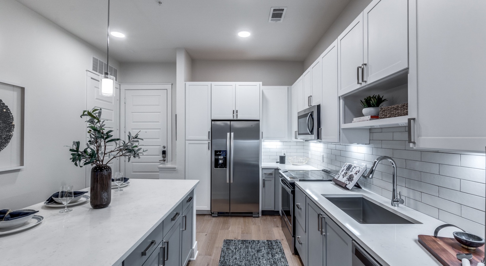 a clean kitchen with stainless steel appliances and white cabinets at The Cedar at  Branch
