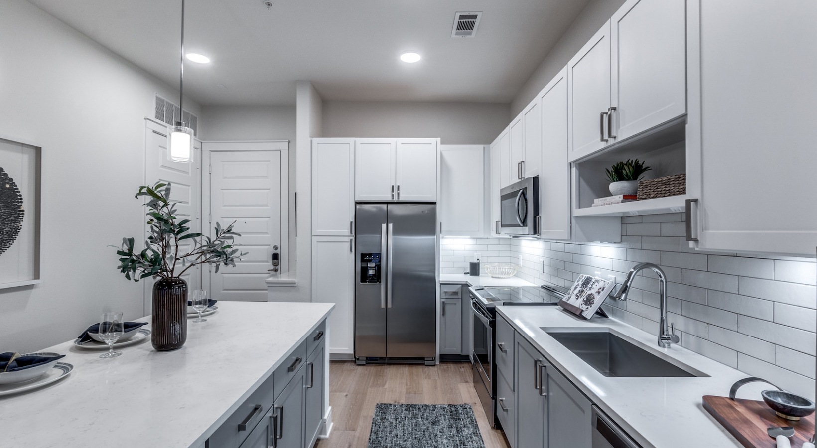a clean kitchen with stainless steel appliances and white cabinets at The Cedar at Branch